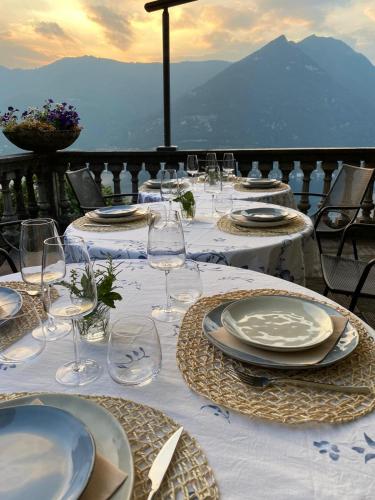 a table with plates and glasses on a table with a view at B&B Villa le Ortensie in Faggeto Lario 