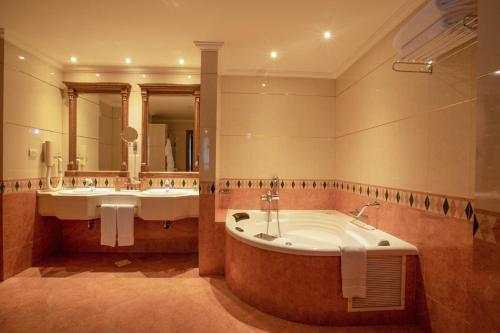 a bathroom with two sinks and a bath tub at Bristol Hotel in Amman