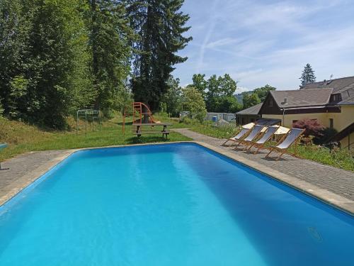 a swimming pool with two chairs and a playground at Penzion Jizera Malá Skála in Malá Skála