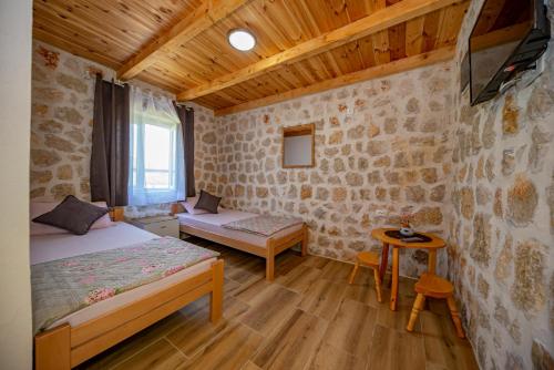 a bedroom with a bed and a table in a room at Ethno house OSOBAK in Virpazar