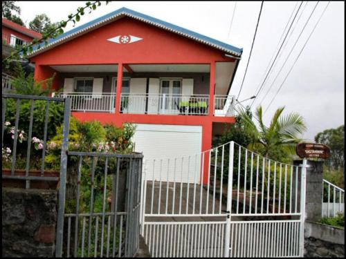 een rood huis met een hek ervoor bij Chez Sandrine in Cilaos