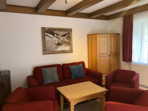 a living room with a red couch and two chairs at Familienappartements Eder - Free entry to Tauern SPA Kaprun included in Kaprun