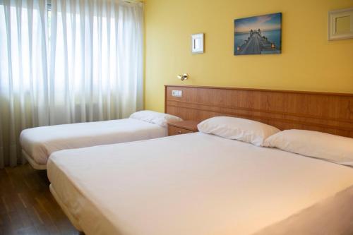 a hotel room with two beds and a window at Hotel Alda Estación Oviedo in Oviedo