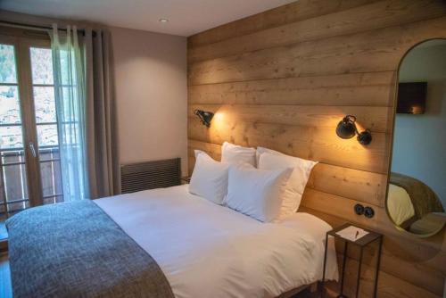 a bedroom with a white bed with a wooden wall at La Ferme in La Clusaz