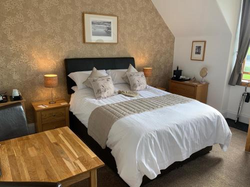 1 dormitorio con 1 cama grande con sábanas y almohadas blancas en Morlea Bed & Breakfast, en Drumnadrochit