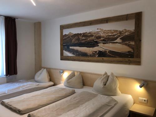 two beds in a hotel room with a painting on the wall at Familienappartements Eder - Free entry to Tauern SPA Kaprun included in Kaprun