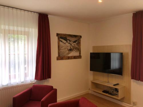 a living room with a tv and a red chair at Familienappartements Eder - Free entry to Tauern SPA Kaprun included in Kaprun