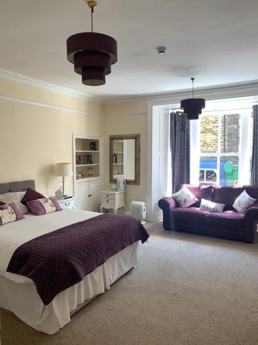 um quarto com uma cama grande e um sofá em Crown Hotel em Pateley Bridge