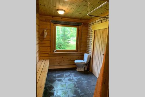 a bathroom with a toilet in a wooden cabin at Pirtsmāja Villa Marta in Cēsis