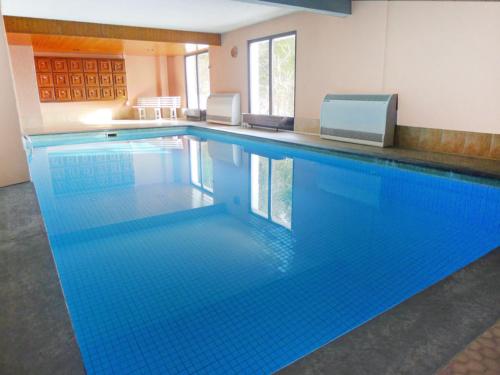 a large swimming pool with blue water in a building at STUDIO CONFORT & DETENTE in Chesières