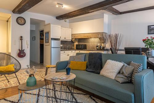un salon avec un canapé bleu et une cuisine dans l'établissement L'Arpege - appartement de charme cœur historique de Vannes, à Vannes