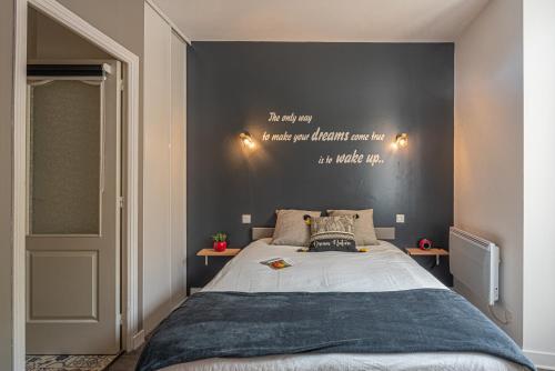 ein Schlafzimmer mit einem großen Bett mit Worten an der Wand in der Unterkunft L'Arpege - appartement de charme cœur historique de Vannes in Vannes