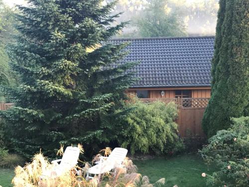 zwei weiße Stühle in einem Garten mit einem Haus in der Unterkunft Ferienhaus Eldena Greifswald Steffi Fasten in Eldena