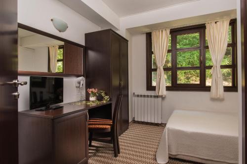 Schlafzimmer mit einem Schreibtisch, einem Bett und einem Fenster in der Unterkunft Family Hotel Bile in Beli Osam