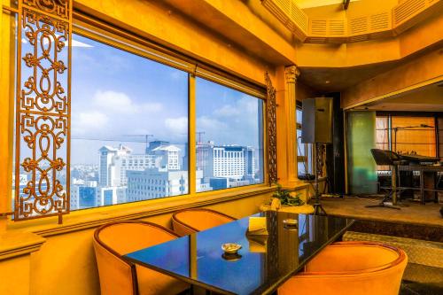 a table and chairs in a room with a large window at Bristol Hotel in Amman