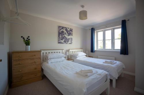 a bedroom with two beds and a dresser and a window at Finch House by RentMyHouse in Bullingham