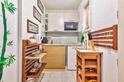 Elle comprend une petite cuisine avec des placards blancs et un réfrigérateur. dans l'établissement RDP triangle d'or - free Parking, à Nice