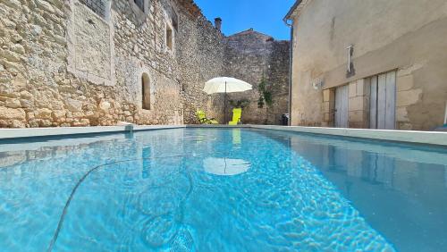 a swimming pool in a building with an umbrella at La maison Bleue in Céreste
