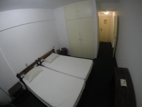 アグアス・デ・リンドイアにあるHotel Cavalinho Brancoのベッド1台とクローゼットが備わる小さな客室です。