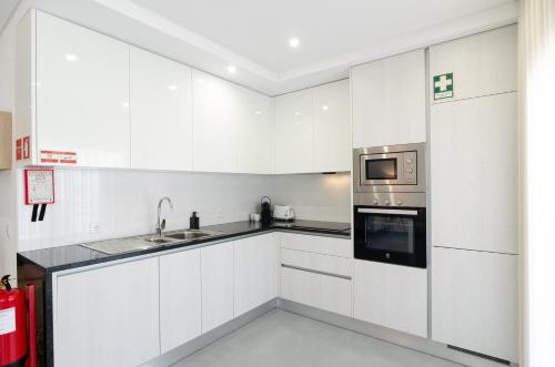 a white kitchen with a sink and a microwave at North Breeze - 2 Bedroom Apartment with Rooftop Pool in Nazaré