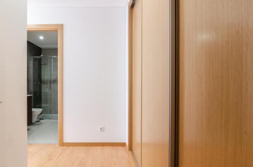 a hallway with a wooden door and a mirror at North Breeze - 2 Bedroom Apartment with Rooftop Pool in Nazaré