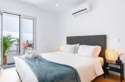 a bedroom with a large white bed and a balcony at North Breeze - 2 Bedroom Apartment with Rooftop Pool in Nazaré