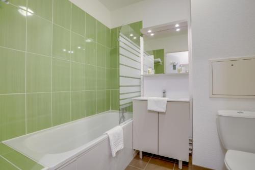 a bathroom with a tub and a sink and a toilet at All Suites Appart Hôtel - Dunkerque Centre in Dunkerque