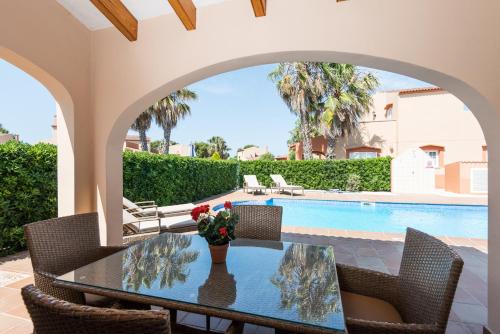 une terrasse avec une table et des chaises ainsi qu'une piscine dans l'établissement Villas Maribel, à Cala Blanca