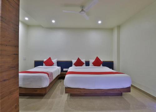 two beds with red pillows in a room at Hotel Kuber in Dwarka