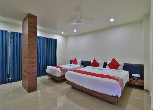 two beds in a bedroom with blue drapes at Hotel Kuber in Dwarka