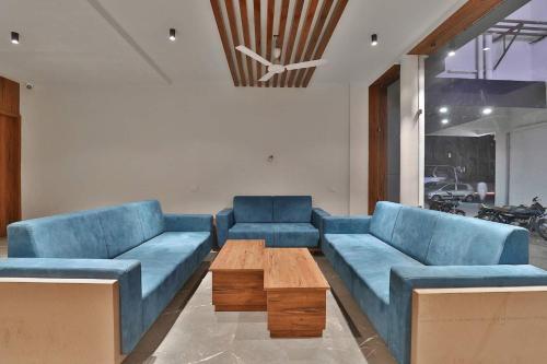 a living room with blue couches and a coffee table at Hotel Kuber in Dwarka