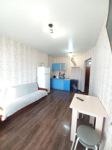 イルクーツクにあるApartament on 30 Deviziiのベッド、テーブル、キッチンが備わる客室です。