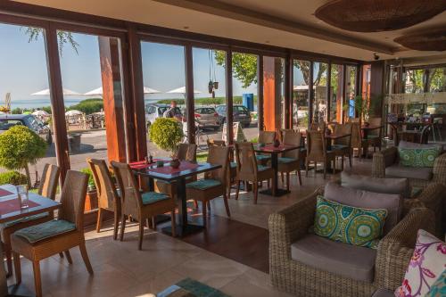 a restaurant with tables and chairs and windows at Mala Garden Design Hotel in Siófok