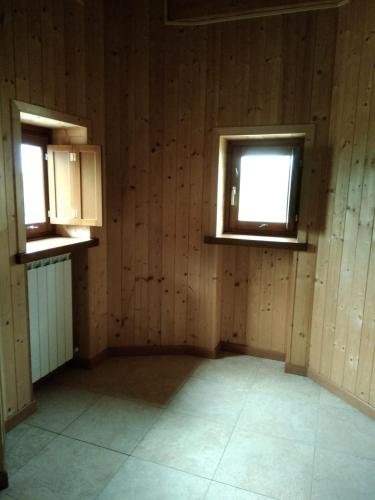 an empty room with wooden walls and two windows at Botton D' Oro in Cornalba