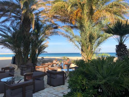 a restaurant on the beach with palm trees and the ocean at Hotel Capo San Vito by Geocharme in San Vito lo Capo