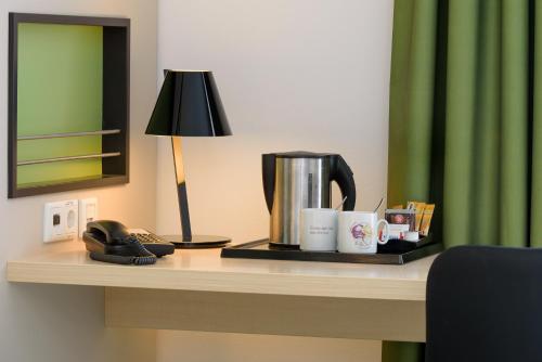 a table with a coffee maker and a lamp on it at Mercure Hotel Hannover Mitte in Hannover