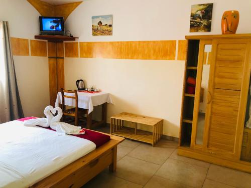 a bedroom with a bed and a table with a tv at Petite Flower Guest House in Talata-maty