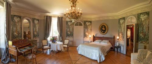 a bedroom with a bed and a table and a chandelier at La Villa Palladienne - Château de Syam in Syam