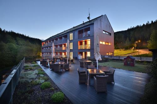 a building with tables and chairs on a wooden deck at Omnia Hotel Relax & Wellness in Janske Lazne