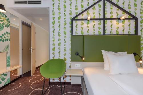 a hotel room with a bed and a green headboard at Mercure Hotel Hannover Mitte in Hannover