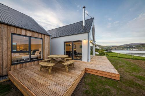 una terraza de madera con una mesa de picnic en una casa en Tides Uig Isle of Skye, en Uig