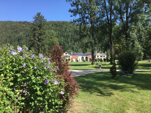 a park with a house in the background with flowers at La Villa Palladienne - Château de Syam in Syam