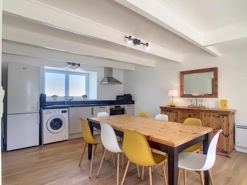 une salle à manger avec une table en bois et des chaises jaunes dans l'établissement Maison 6 pers proche centre ville, à Bréhal