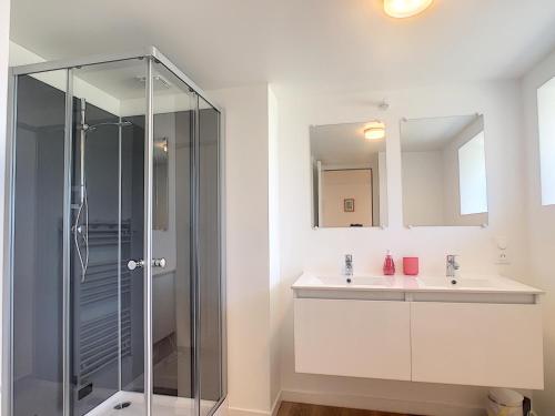 a bathroom with a glass shower and a sink at Maison 6 pers proche centre ville in Bréhal