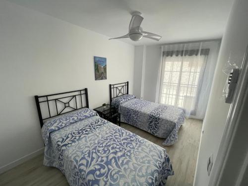 1 dormitorio con 2 camas y ventilador de techo en Escondite Real - Royal Hideaway - Vivienda con Fines Turísticos Hospital de San Miguel, en Jaén