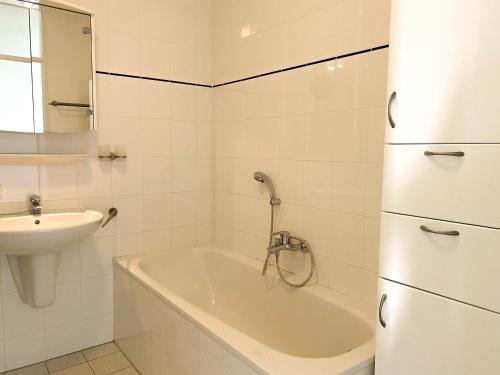 ein weißes Badezimmer mit einer Badewanne und einem Waschbecken in der Unterkunft Hello Zeeland - Appartement Port Scaldis 19-012 in Breskens