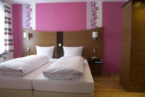 1 dormitorio con 2 camas y pared de color rosa en Hotel Dampfmühle, en Enkirch