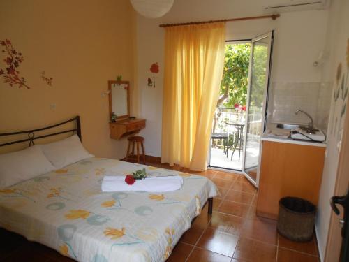 a bedroom with a bed and a kitchen with a balcony at Elenas Garden in Kavos