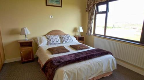 een slaapkamer met een bed en een groot raam bij The Bungalow in Doonbeg