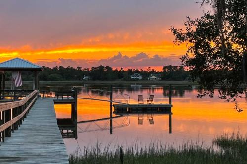 a dock on a lake with a sunset in the background at Nantucket Cottage with Fishing Dock and Sunsets in Fernandina Beach